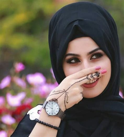A Woman Wearing A Black Hijab And Holding Her Hand Up To Her Face