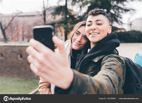 Two Women Lesbian Couple Outdoors Using Smart Phone Taking Selfie Stock