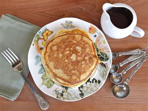 Pancakes On A Plate With Coffee And Spoons Next To It Sitting On A Table