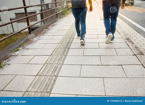 Two People Walking On A Sidewalk In The Morning Stock Photo Image Of