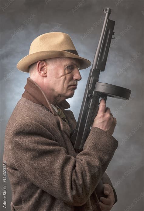 1940s Male Gangster Holding A Machine Gun On A Grey Smoky Background