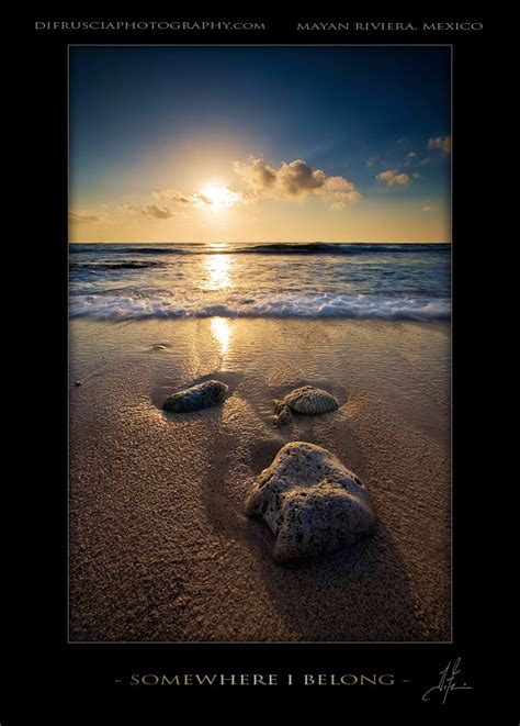 Two Rocks In The Sand Near The Ocean At Sunset With Clouds And Sun