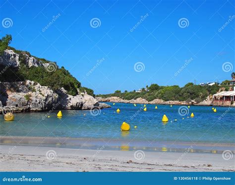 View Of The Beach And Bay At Cala Santandria In Menorca With Yellow