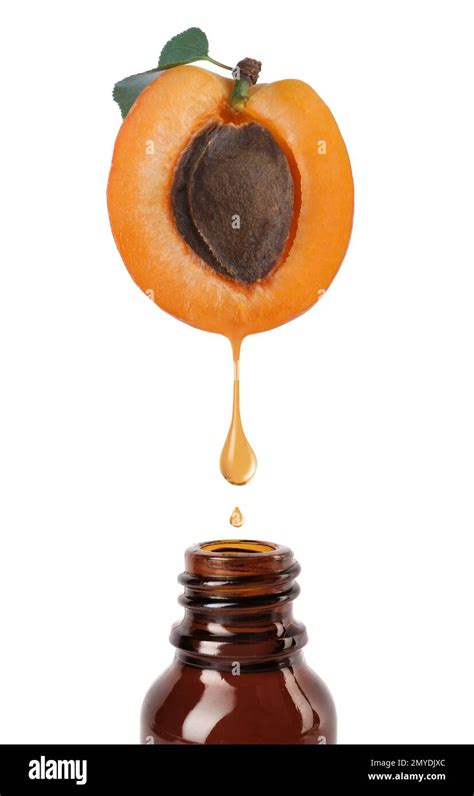 Apricot Kernel Oil Dripping From Fresh Fruit Half Into Glass Bottle On