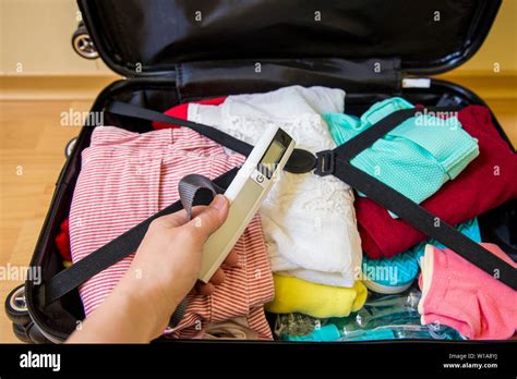 Woman Packing Digital Luggage Scale In Luggage To Avoid Overweight