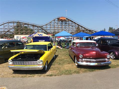 Several Classic Cars Parked Next To Each Other In Front Of A Roller Coaster