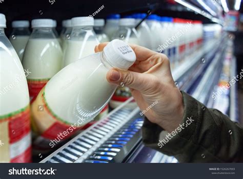 Womans Hand Holding Milk Bottle In Supermarket Man Shopping Milk In