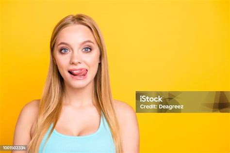 portrait of lovely blond girl licking upper lip with tongue out and looking at camera isolated