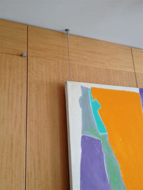 How do i prevent a painting from tilting forward when hung? Hanging Art from the Ceiling - ILevel