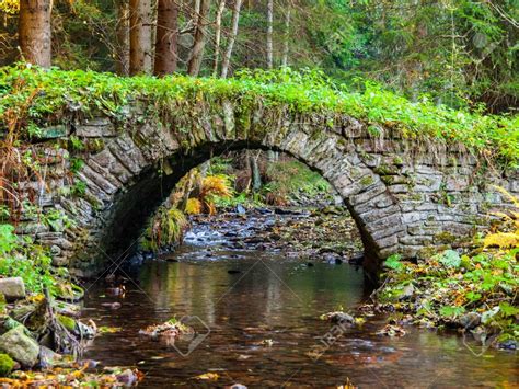 Picturesque Old Stone Bridge Over Calm Brook In An Autumn Forest Stock