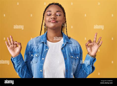 african american woman with braids standing over yellow background relaxed and smiling with eyes