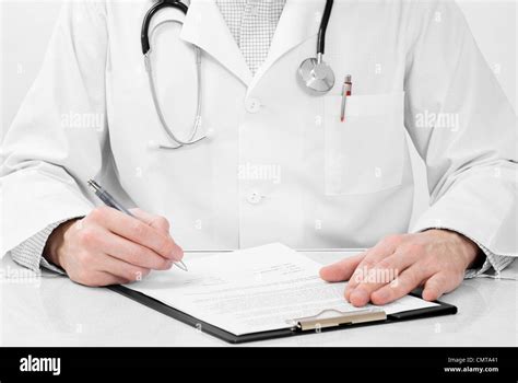 Doctor With Stethoscope And Clipboard Writing Something While Sitting At His Working Place Stock