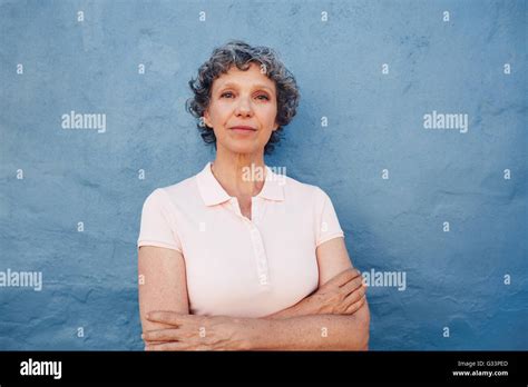 Portrait Of Confident Mature Woman Standing With Her Arms Crossed Against Blue Background Stock