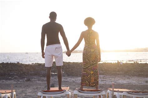 Black Race African Couple Enjoying The Warm And Golden Sunset Over The Beach Standing On The