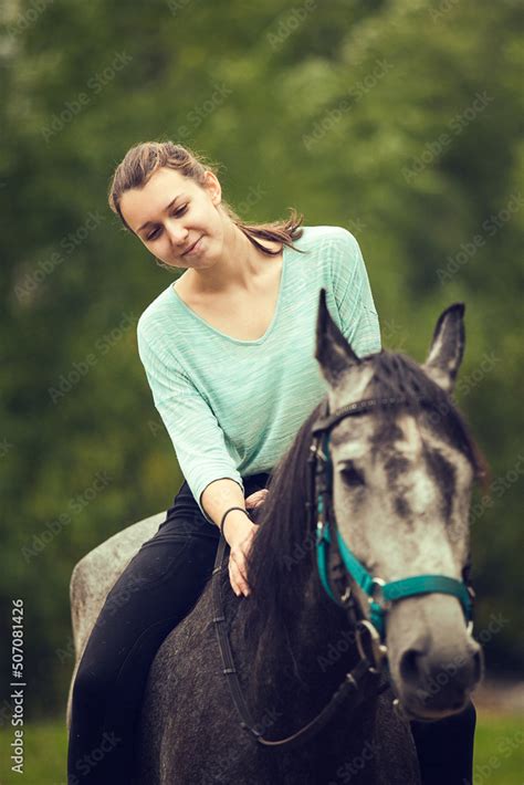 Young Girl Sits Astride A Grey Horse Portrait Close Up Stock Photo