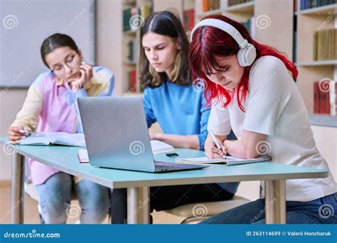 Group Of Teenage Students Study At Their Desks In Library Class Stock