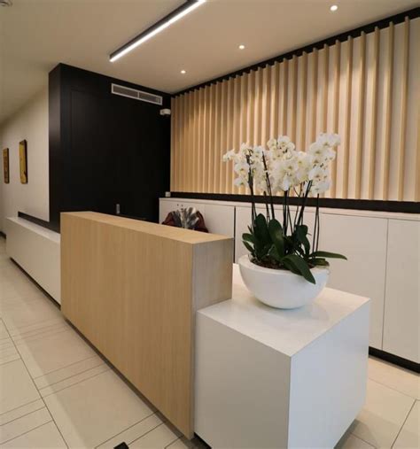 A Planter With White Flowers Sits On A Counter In An Office Lobby Area