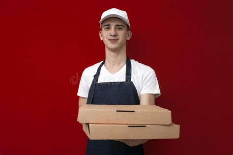 Retrato De Un Joven Repartidor De Pizza Con Uniforme En Un Fondo Rojo