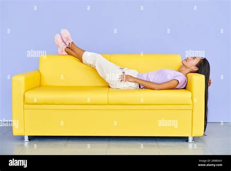 pretty asian woman relax after lying on yellow sofa after hard work rest comfort concept stock