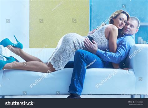 Passionate Couple Embracing On Sofa And Looking At Camera Stock Photo