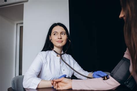 여성 의사의 사무실에 방문하는 동안 혈압 검사를받는 성인 여성 프리미엄 사진