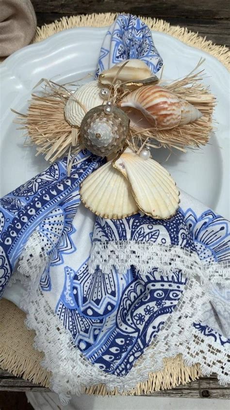 A White Plate Topped With Seashells On Top Of A Blue And White Table Cloth