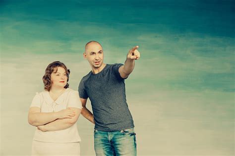 A Plump Redhaired Attractive Woman And A Tall Bald Man On A Blue Background Look To The Side He