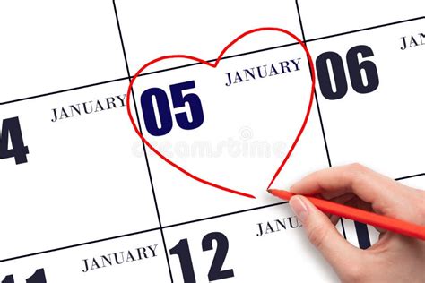 A Woman S Hand Drawing A Red Heart Shape On The Calendar Date Of 5