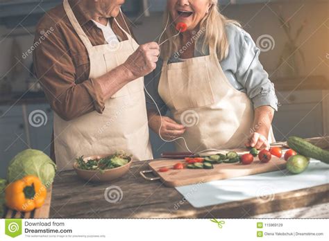 joyful mature husband feeding wife with vegetable stock image image