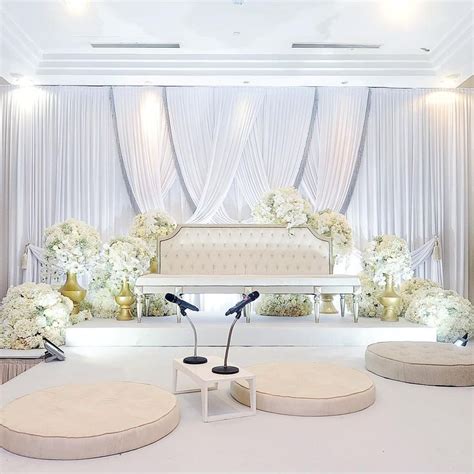 A White Wedding Ceremony Setup With Flowers On The Stage