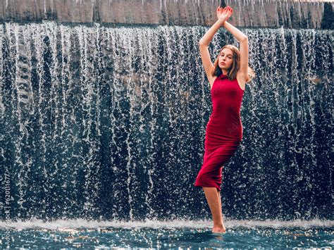 teen ager girl in high fashion red dress posing in water water fall behind her back prom