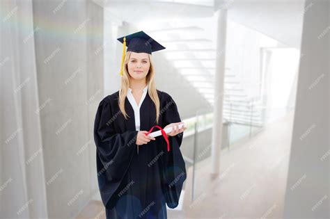 Premium Photo Blonde Student In Graduate Robe Holding Up Her Diploma