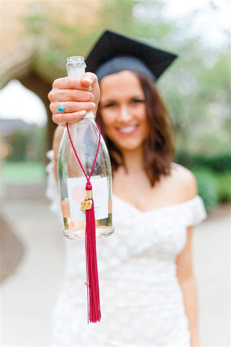 A Woman Wearing A Graduation Cap And Gown Holding Up A Bottle With A