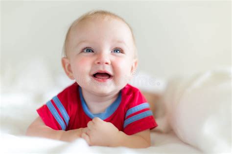 Happy Adorable Baby Laughing And Playing On Soft White Bed Stock Image