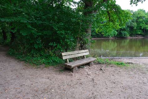 Empty Old Rusticweathered Wooden Bench Overlooking The Beautiful Lake