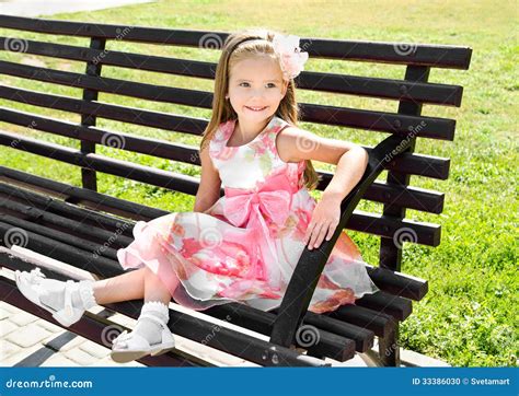 Outdoor Portrait Of Little Girl Sitting On A Bench Stock Photo Image