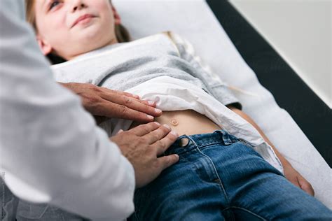 Exam Doctor Checks Belly Of Young Girl Stocksy United