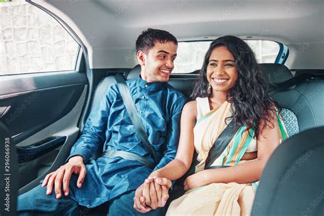 beautiful indian couple in ethnic dress traveling on a back seat of a car holding hands and