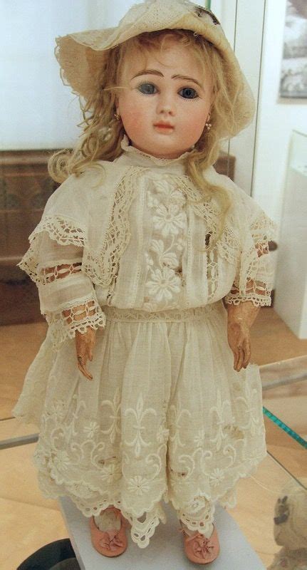 An Antique Doll Is On Display In A Glass Case At The Museum Wearing A