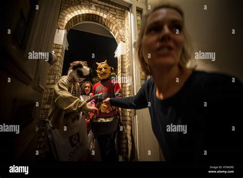 A Woman Answers The Door To Halloween Trick Or Treaters Stock Photo Alamy