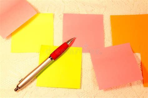 A Ballpoint Pen And Blank Sticky Notes In Orange Yellow And Pink