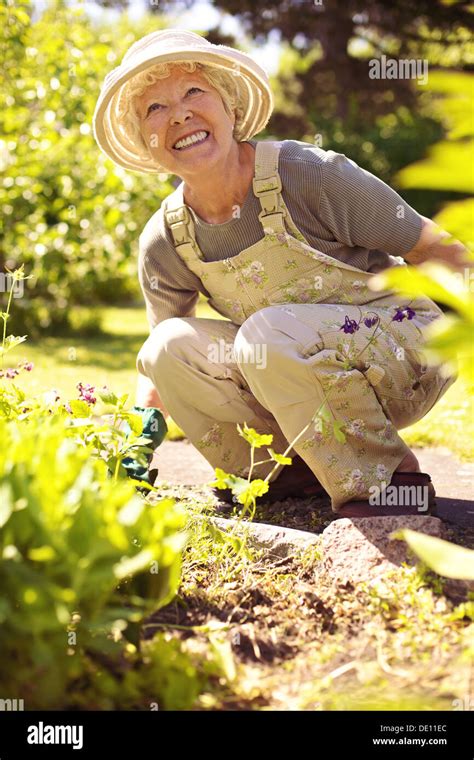 Senior Woman Happily Working With Plants In Her Garden Old Woman