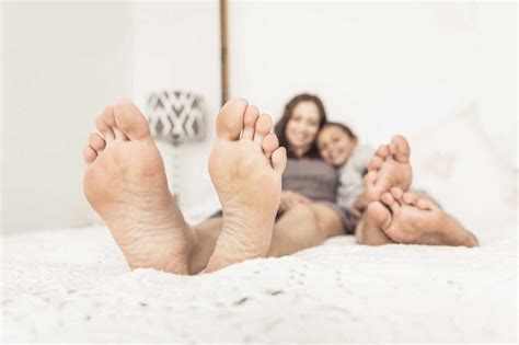 Crop View Of Mother And Daughter Lying Barefoot On Bed Stock Photo