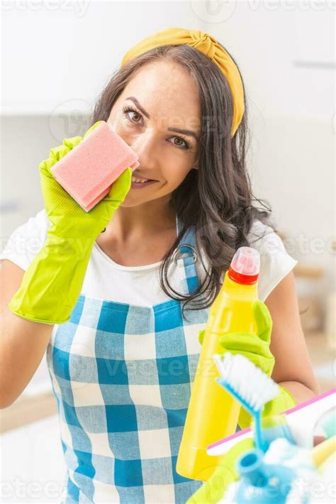 Sexy Young Woman Smiling Into The Camera Holding A Dish Washing Sponge In Her Rubber Gloves