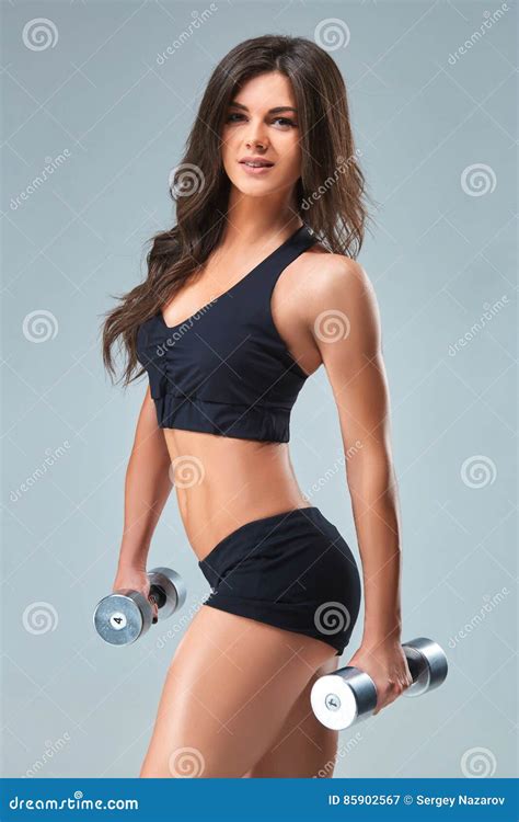 Athletic Woman Pumping Up Muscles With Dumbbells On Gray Background