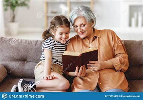 Cheerful Grandmother And Granddaughter Reading Book Together Stock