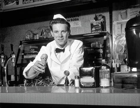 1950s Smiling Young Man Soda Jerk Leaning Across Counter Looking At
