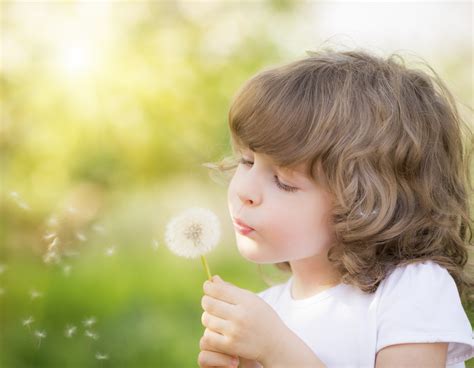 Happy child blowing dandelion - Raising World Changers
