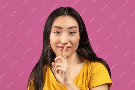 premium photo mysterious asian lady holding finger near lips and looking at camera pretty