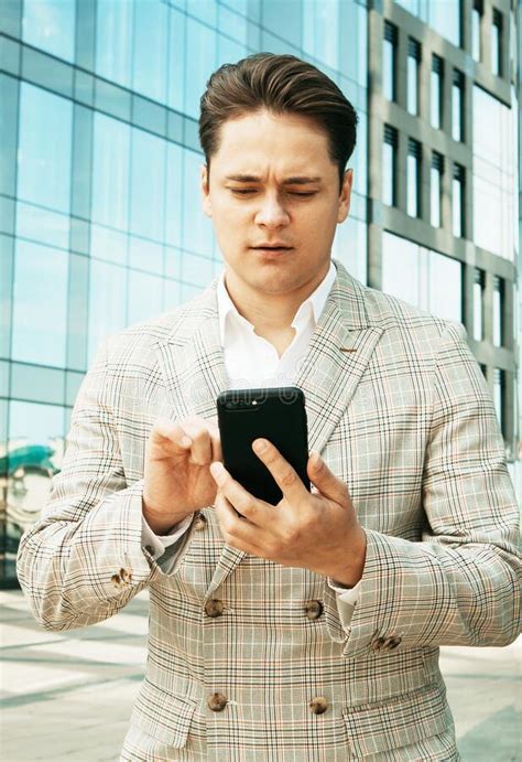 Businessman Using Mobile Phone App Texting Outside Of Office In Urban